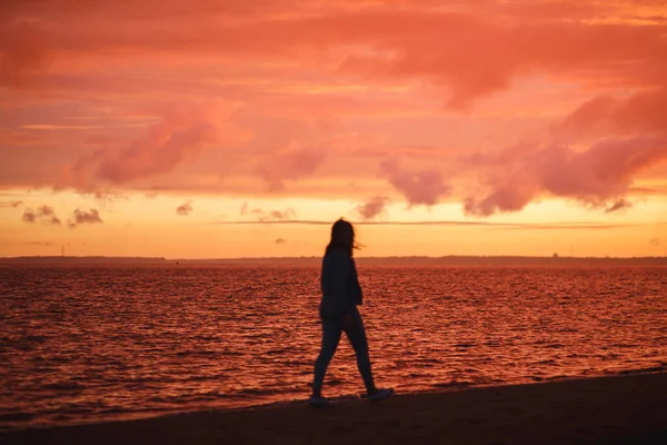 Frau spaziert allein am Strand und betrachtet den bunten Sonnenuntergang nach dem Regen. Schöne Landschaft, Fokus auf Wellen — Stockfoto