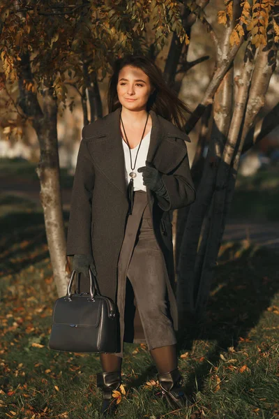 在美丽的阳光明媚的秋天小巷，穿着皮毛外套，提着手提箱的时髦的高加索女孩 — 图库照片