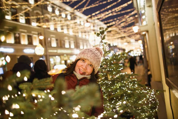 Retrato noturno ao ar livre de mulher na moda jovem no chapéu de inverno com pompom. Feliz nas decorações da rua de Natal. Iluminação de rua noturna em Moscou — Fotografia de Stock