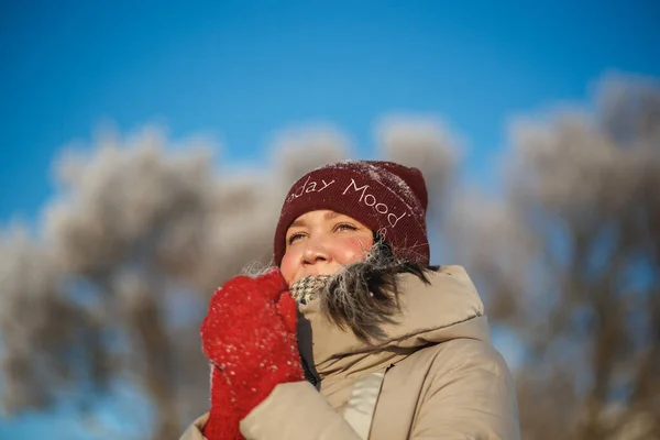 Kırmızı şapkalı ve kırmızı eldivenli mutlu bir genç kadın. Güneşli bir günde mavi gökyüzüne karşı. — Stok fotoğraf