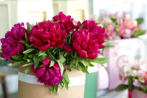 Three dark pink peonies flowers in a vase indoors. Spring flowers. Beautiful peonies in a bouquet.