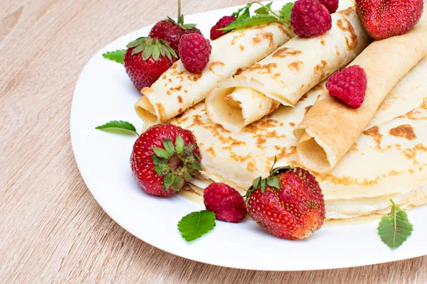 Çilekli ve ahududulu krep. Tabakta ahududu ve çilekli krep. Tabakta ahududu, çilek ve ahşap tahtayla krep..