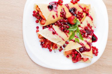 Tabakta yaban mersinli ve çilekli krep. Böğürtlenli krep, çilek ve çikolata şurubu. Kahvaltıda krep, çilek ve çilek.