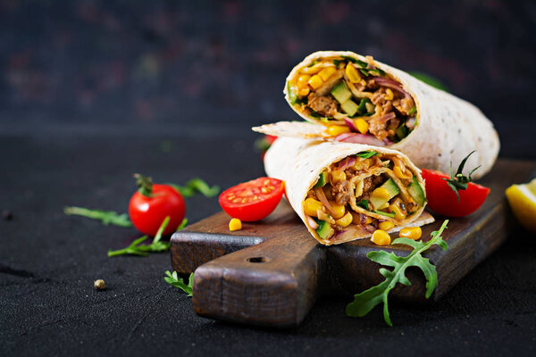 Burritos wraps with beef and vegetables on  black background