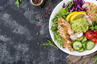 ızgara tavuk, quinoa, domates, guacamole, havuç, kırmızı lahana, salatalık ve roka salatası üstten görünüm 