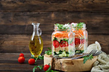 salata quinoa, roka, turp, domates ve salatalık ahşap arka plan üzerinde cam kavanozlara yakın çekim