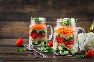 salata quinoa, roka, turp, domates ve salatalık ahşap arka plan üzerinde cam kavanozlara yakın çekim
