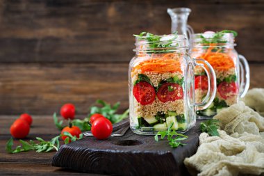 salata quinoa, roka, turp, domates ve salatalık ahşap arka plan üzerinde cam kavanozlara yakın çekim