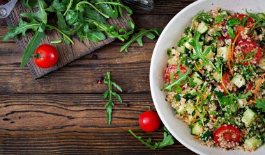 salata quinoa, roka, turp, domates ve salatalık kase üstten görünüm ahşap arka plan üzerinde