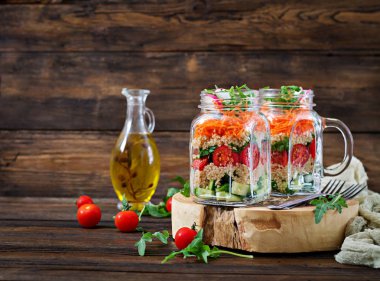 salata quinoa, roka, turp, domates ve salatalık ahşap arka plan üzerinde cam kavanozlara yakın çekim