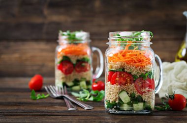 salata quinoa, roka, turp, domates ve salatalık ahşap arka plan üzerinde cam kavanozlara yakın çekim