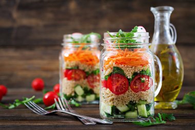 salata quinoa, roka, turp, domates ve salatalık ahşap arka plan üzerinde cam kavanozlara yakın çekim