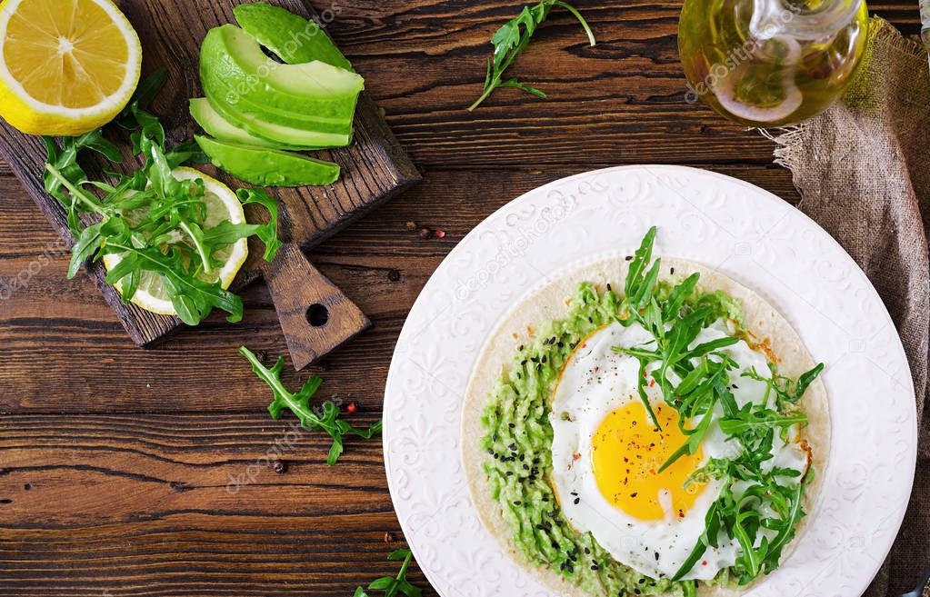 top view of tacos with guacamole, fried egg and arugula