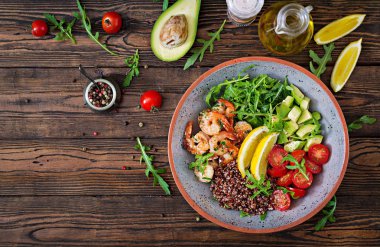 Lezzetli sağlıklı Buda kase karides, domates, avokado, quinoa, limon ve roka ahşap masa üzerinde. Sağlıklı gıda. Üstten görünüm