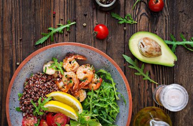 Lezzetli sağlıklı Buda kase karides, domates, avokado, quinoa, limon ve roka ahşap masa üzerinde. Sağlıklı gıda. Üstten görünüm
