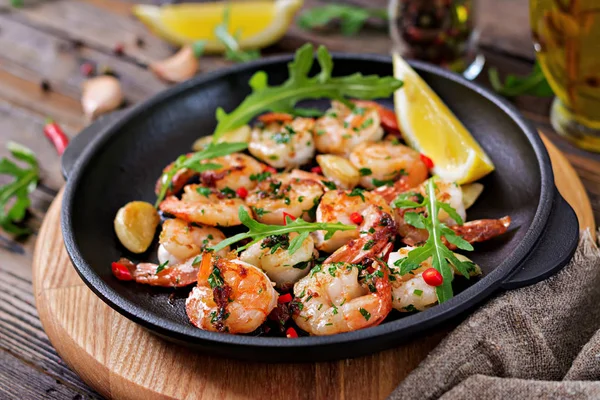 Shrimps roasted in garlic butter with lemon and parsley on wooden background. Healthy food.