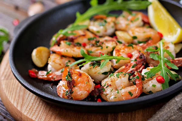 Shrimps roasted in garlic butter with lemon and parsley on wooden background. Healthy food.