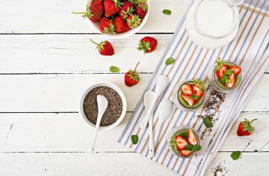 Detoks ve kavanoz sağlıklı kahvaltı. Vegan Hindistan cevizi sütü chia tohum pudingi çilek ve kivi ile. Üstten görünüm.