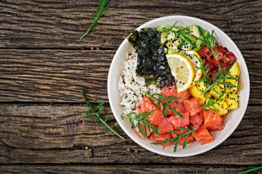 Hawaiian Somon Balık poke kaseyle pirinç, avakado, mango, domates, susam ve yosunlar. Buda kase. Diyet yemekleri. Üstten görünüm. Düz yatıyordu