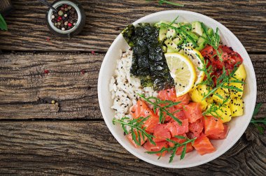 Hawaiian Somon Balık poke kaseyle pirinç, avakado, mango, domates, susam ve yosunlar. Buda kase. Diyet yemekleri. Üstten görünüm. Düz yatıyordu