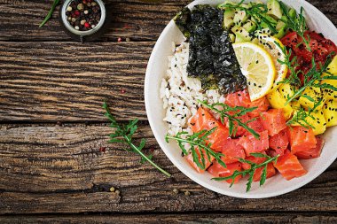 Hawaiian Somon Balık poke kaseyle pirinç, avakado, mango, domates, susam ve yosunlar. Buda kase. Diyet yemekleri. Üstten görünüm. Düz yatıyordu
