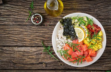 Hawaiian Somon Balık poke kaseyle pirinç, avakado, mango, domates, susam ve yosunlar. Buda kase. Diyet yemekleri. Üstten görünüm. Düz yatıyordu