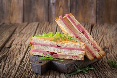 Club sandviç - panini jambon ve peynir ahşap arka plan üzerinde. Piknik gıda.