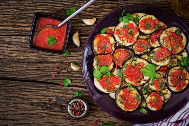 Patlıcan, domates sosu, sarımsak, kişniş ve nane ile ızgara. Vegan gıda. Izgara patlıcan. Üstten görünüm. Düz yatıyordu