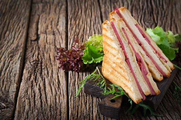Club sandviç - panini jambon ve peynir ahşap arka plan üzerinde. Piknik gıda.