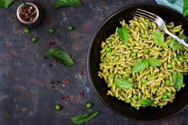 Düdük makarna pesto sosu, yeşil bezelye ve karanlık kapta çatalla hizmet fesleğen ile üstten görünüm.