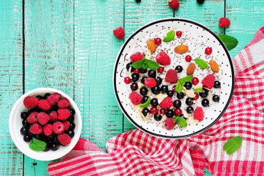 Puding ahududu, böğürtlen ve nane plaka turkuaz ahşap masa üzerinde yukarıdan vegan badem süt chia tohum.