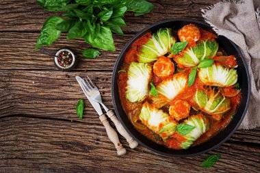 Üstten görünüm lahana rulo pilav ile doldurulmuş tavuk fileto ahşap zemin üzerine domates sos.