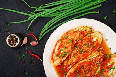 Karanlık masada Kimchi lahana beyaz plaka üstten görünüm.