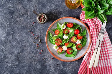 Caprese salatası tabağına gri masada damalı peçete ile servis üstten görünüm.