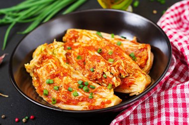 Kimchi lahana kırmızı kareli peçete ile siyah plaka üstten görünüm.