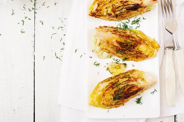 Vegan üstten görünüm Beyaz ahşap zemin üzerinde lahana biftek ızgara. 