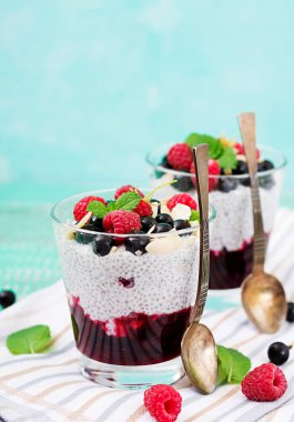 Vegan badem süt chia tohum puding ahududu, böğürtlen ve nane ile kaşık bardaklarda.