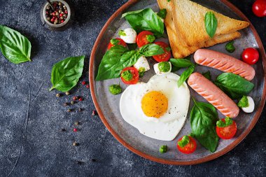 Kahvaltı üstten görünüm Sevgililer günü - kızarmış yumurta, sosis, tost ve caprese salatası.