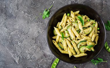 Pesto sos, kabak, yeşil bezelye ve fesleğen ile penne makarna. İtalyan yemeği. Üstten görünüm. Düz kopya alanı ile yatıyordu