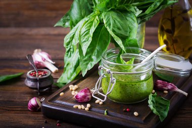 Ev yapımı pesto sos taze fesleğen, çam fıstığı ve sarımsak ahşap arka plan üzerinde Kapat. 