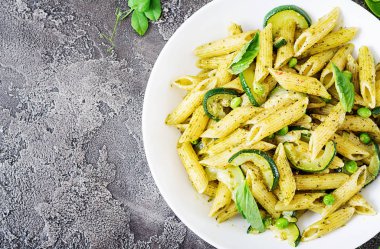 Pesto sos, kabak, yeşil bezelye ve fesleğen gri taş arka penne makarna ile plaka. Kopya alanı ile üstten görünüm