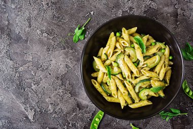 pesto sos, kabak, yeşil bezelye ve gri arka plan, kopya alanı ile üstten görünüm üzerinde fesleğen ile penne makarna ile pan