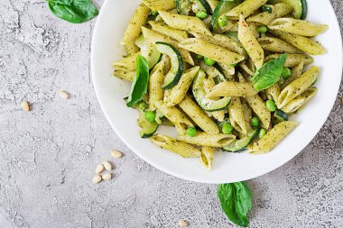 Pesto sos, kabak, yeşil bezelye ve fesleğen ile penne makarna. İtalyan yemeği. Üstten görünüm. Düz yatıyordu.