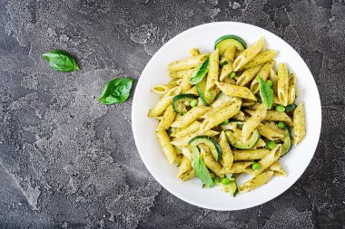Pesto sos, kabak, yeşil bezelye ve fesleğen gri taş arka penne makarna ile plaka. Kopya alanı ile üstten görünüm