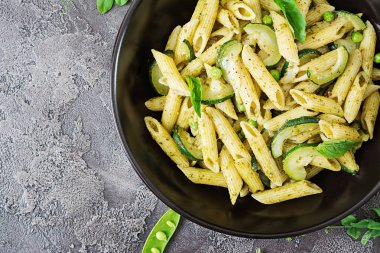 pesto sos, kabak, yeşil bezelye ve gri arka plan, kopya alanı ile üstten görünüm üzerinde fesleğen ile penne makarna ile pan
