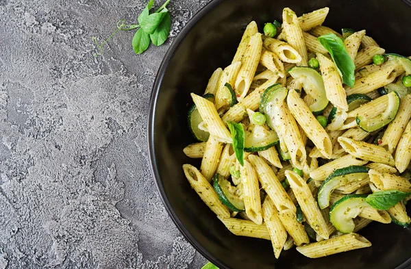 pesto sos, kabak, yeşil bezelye ve gri arka plan, kopya alanı ile üstten görünüm üzerinde fesleğen ile penne makarna ile pan