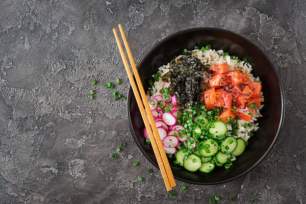 Hawaiian salmon fish poke bowl with rice, radish,cucumber, tomato, sesame seeds and seaweeds. Buddha bowl. Diet food. Top view. Flat lay