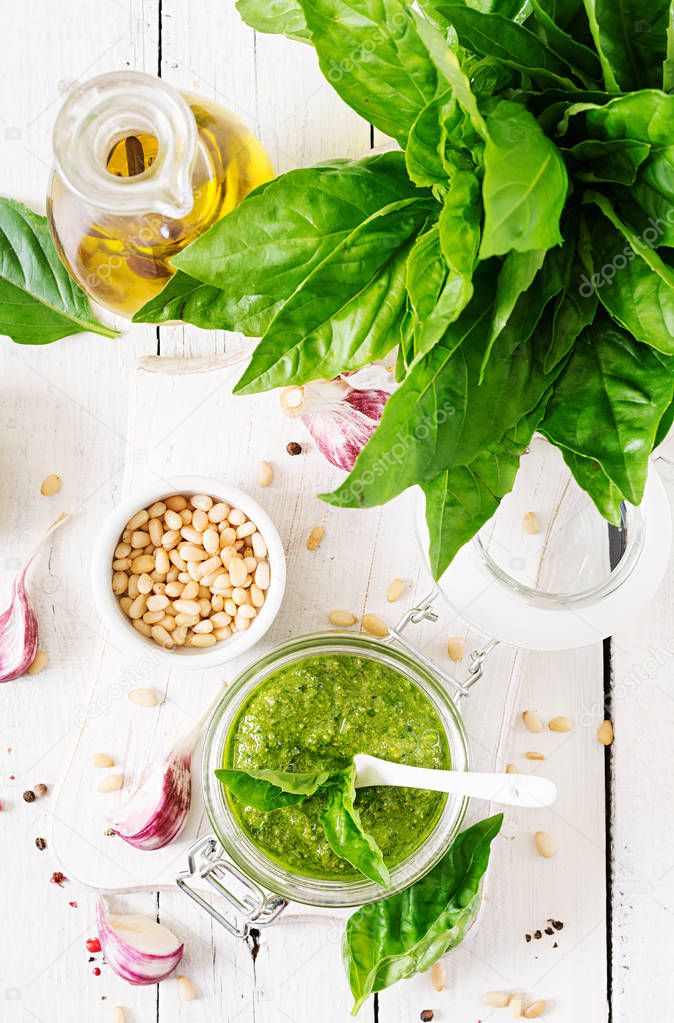 Homemade pesto sauce fresh basil, pine nuts and garlic on white wooden background. Italian food. Top view. Flat lay.