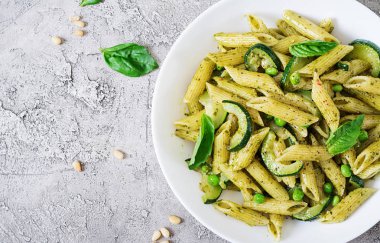 Pesto sos, kabak, yeşil bezelye ve fesleğen ile penne makarna. İtalyan yemeği. Üstten görünüm. Düz yatıyordu.