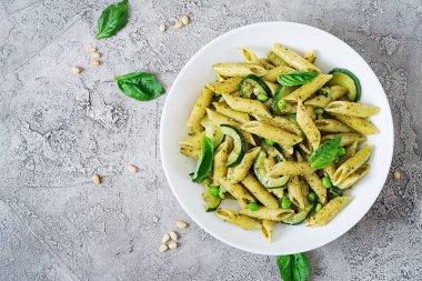 Pesto sos, kabak, yeşil bezelye ve fesleğen ile penne makarna. İtalyan yemeği. Üstten görünüm. Düz yatıyordu.